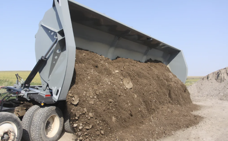 Side Dump Trailer dumping a load of soil